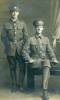 Stuido photo of Eric and Walter. Wearing WW1 uniforms, Walter is holding a swagger stick. Hats and insignia.