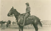 Jack on horseback with  horses in background 