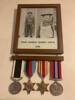 Image of departure photos of John Charles Robert Smith in military uniform with rifle. Service medals hanging below photographs