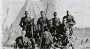 Members of the New Zealand Army Rifles Band photographed outside a tent, possibly somewhere in Palestine. Back row: BDO Morrison, BDO Booth, BDO Dunn, BDO Kay; Middle row; BDO Drake, BDO Shepperd, BDO Mann, Front Row: BDO Bruton, BDO Jones, BDO Andrews.
Further notes from the back of the original photo: BDO Morrison learned his instrument out here. BDO Booth could read music but learned the clarinet after being in the AMR. BDO Dunn is all round instrumentalist, BDO Kay played a clarinet in NZ, BDO Drake played in the 3rd AMR in Auckland, BDO Sheppard did likewise, BDO Mann is a cellat of some fame. Out here after being in the Machine and up to Berrsheba. BDO Bruton joined after the Berrsheba to Jaffa push. He played in the Glays Riot Band, Dunedin