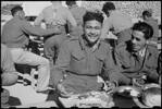 W Ereatara (Bay of Plenty) sits down to a hangi-cooked Christmas dinner at the Maori Training Depot in Maadi Camp, Egypt. Photograph taken on 25 December 1943 by George Robert Bull.