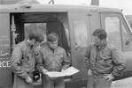 L-R: Flying Officer GL Claxton, Flying Officer NR McKenzie and Sergeant MD Burke, looking at a map, in front of No. 3 Squadron Iroquois NZ3804. This No. 3 Squadron crew assisted the Police Armed Offender's Squad in their search for an armed felon, near Dunedin, who shot a person in a car. PR1140-3-74 Crown Copyright 1974. Air Force Museum of New Zealand CC-BY-NC 3.0.