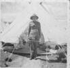 Portrait, standing to attention outside tent, folded blankets, bedding and floor of tent visible, this photograph was either taken in Military camp in New Zealand or in Camp in Egypt. - This image may be subject to copyright