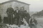 Group, WW2, 5 airmen outside a stone hut, with dog. Left to right: Albert Cliffe; Covich; Merv Thorpe, Bob Watkins; Ginger Thompson with Matilda and puppies - This image may be subject to copyright