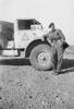 F.G. Moxley, portrait, full length, leaning against truck in desert - This image may be subject to copyright