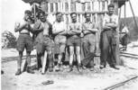 Group, WW2, POW camp, 1943 6 men standing leaning against wooden [building?], Nicoll is second from left. - This image may be subject to copyright