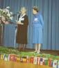 Reunion, war brides, Mt Eden War Memorial Hall, Auckland ca. mid 1990s, 2 women likely the coordinators of the reunion, giving a speech standing on the stage, international flags decorating the front of the stage - This image may be subject to copyright
