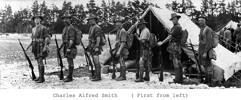 Group, WW1, 7 soldiers standing in a line all wearing shorts, sleeves rolled up, rifles, knap sacks, daggers and other equipment, snow on the ground, line of pine trees and two tents in background. other men in background. - No known copyright restrictions