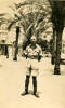 Portrait Leslie Gordon Jackson (66110) in Egypt with palm trees and building behind him. Postcard stamped on reverse. - This image may be subject to copyright