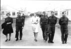 Group 4 soldiers and 2 women walking down road in camp John Sherson is 3rd man from left walking beside woman in white - This image may be subject to copyright