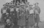 Group, in great coats and tin hats, men under command of Sergeant Thomson (centre front) standing outside at Papakura Training Camp before departure. - This image may be subject to copyright