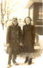 Group, WW2, airman and woman, Mills in overcoat, with an unidentified woman also in overcoat, both smiling standing in front of a car, house, perhaps snow on the car rear window - This image may be subject to copyright