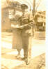 Group, WW2, airman, Mills and his friend Mrs Knoll. Mills has cap, jacket with wings badge, embracing his friend. Standing in front of large houses, trees without leaves, pavement - This image may be subject to copyright