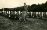 Len standing beside Jesse Pearse's granite gravestone, other graves and Cross of Sacrifice in the background at Maidstone Cemetery, Kent, England - This image may be subject to copyright