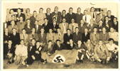 Group, men informally arranged, holding glasses and a nazi flag. Photograph taken at the reunion of ex POW from Lutf VI, held in Tokoroa c. 1956-8, Ronald Moore (NZ404554) is second from left in back row. The only other person identified is Ivan Mears, 5th from right in second row from front. (Album of Ronald Moore (NZ404554)) - This image may be subject to copyright