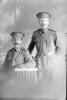 3/4 portrait of Sapper William Coldicutt, Reg No 4/1244 (standing), and Sapper Oswald Charles Cossey, Reg No 4/1251 (seated) both of the New Zealand Tunnelling Company (Photographer: Herman Schmidt, 1915). Sir George Grey Special Collections, Auckland Libraries, 31-C310. No known copyright.