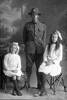 Full length portrait of Trooper Thomas Robert Catton, Reg No 13/2543, of the Auckland Mounted Rifles, 8th Reinforcements and two girls, his sisters Doris and Rena. (Photographer: Herman Schmidt, 1915). Sir George Grey Special Collections, Auckland Libraries, 31-C1942. No known copyright.