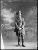 Full length portrait of Colonel James Neil McCarroll, with a moustache, wearing the uniform of the 11th North Auckland Mounted Rifles, campaign medals (Photographer: Herman Schmidt, ). Sir George Grey Special Collections, Auckland Libraries, 31-WP880A. No known copyright.