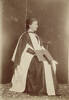 Full length seated portrait of Grace Russell, later Grace de Courcy, the second New Zealand woman to qualify as a doctor, in graduation gown, photographed in Brussels in 1898. Sir George Grey Special Collections, Auckland Libraries, 1050-2. Restrictions on use may apply.