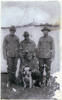 Photograph of Rifleman Thomas Samuel Tooman (s/n 26/918), with Caesar, the mascot of A Company, 4th Battalion, N.Z.R.B. Caesar's handler, standing on left and Caesar, being held by Private Albert Edward Griffin (s/n 3/1513). The other men are unidentified. Image kindly provided by Patricia Stroud. Image may be subject to copyright restrictions.