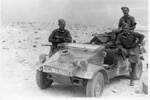 Photograph of Major Arthur Claude Weddell 6532, 3 men posing by a vehicle. The caption reads: Right to left: "Arty" Pearce, George Parsons & Claude Weddell with captures equipment and souvenirs, during advance in desert November 1942. The car is the "so called Peoples" car of Germany. Image kindly provided by Howard Weddell (June 2018). Image may be subject to copyright restriction.