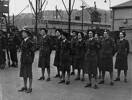 Flight of women on the docks at Wellington, part of the Victory Contingent to London. Front Row L to R: S/Sgt J L Copeland, Sgt J S Milne, Cpl E M Tuapawa, Sgt. C E Reid. Middle Row, WAL E J McGovern, Sgt N C Mercer, Cpl J Beasley, Back Row. Sgt. C F Bryers, Cpl J Mitford-Taylor, Sgt J M Gerrie. Image from the EJ Miller personal album held by the Air Force Museum of New Zealand. Image kindly provided by Air Force Museum of New Zealand CC BY NC 3.0.