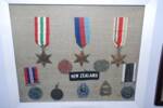 Photograph of Ernest Leslie Garth Cattermole's framed Second World War service medals, badges, identity tags and 'New Zealand' shoulder patch. Image kindly provided by Lynette Low (September 2020).