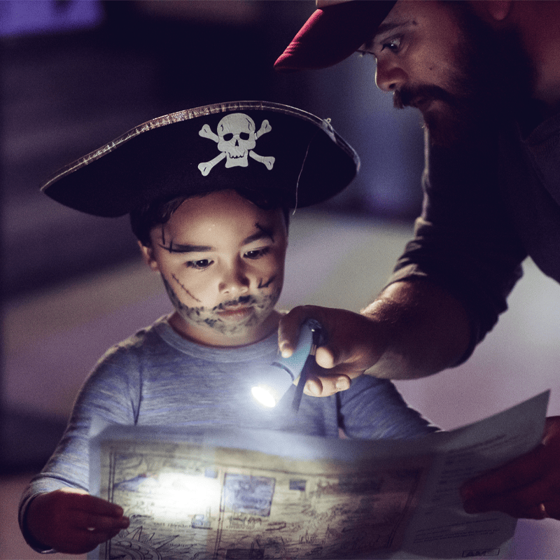 Little boy dressed as a pirate using a torch to explore the Museum at night